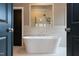 Modern bathroom with a freestanding tub, tiled walls, and a window view at 9520 Wood River Dr, Zebulon, NC 27597