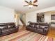 Open living room with leather furniture, ceiling fan, hardwood floors, and view of the kitchen at 67 Meherrin Ct, Clayton, NC 27527