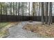 Fenced backyard with fire pit, gravel path, and mature trees at 7800 Secluded Acres Rd, Apex, NC 27523