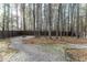 Private backyard with a fire pit, gravel pathway, and mature trees, enclosed by a new wooden fence at 7800 Secluded Acres Rd, Apex, NC 27523