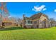 Large backyard with green grass, trees, a screened-in porch, and a retaining wall at 4109 Cheek Point Pl, Burlington, NC 27215