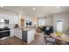Open-concept kitchen and living area with white cabinets, stainless steel appliances, and wood floors at 447 Belgian Red Way, Wake Forest, NC 27587