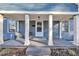 Inviting front porch with grey concrete flooring, two chairs, and white columns at 810 Brooklyn St, Raleigh, NC 27605