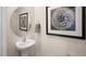Powder room with pedestal sink, round mirror, and framed art at 454 Belgian Red Way, Wake Forest, NC 27587