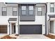 Modern townhome exterior with gray and white siding, a black garage door, and landscaping at 1042 Westerland Way # 213, Durham, NC 27703