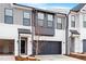 Townhome exterior featuring gray and white siding, a black garage door, and a tree in front at 1042 Westerland Way # 213, Durham, NC 27703