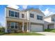 Two-story house with stone and white vinyl siding, a covered porch, and a two-car garage at 38 Tributary Way, Fuquay Varina, NC 27526