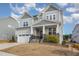 Two-story house with gray siding, stone accents, and a three-car garage at 305 Ocean Jasper Dr, Holly Springs, NC 27540