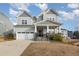 Two-story house with gray siding, stone accents, and a three-car garage at 305 Ocean Jasper Dr, Holly Springs, NC 27540