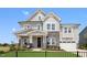 Two story house with gray siding, stone accents, and a three-car garage at 111 E Fountainhead Ln # 154, Garner, NC 27529