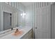 Bathroom with pink sink, striped wallpaper and white cabinets at 3904 Hawthorne Rd, Rocky Mount, NC 27804