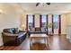 Living room with hardwood floors, leather sofas, and large windows with burgundy curtains at 360 Skymont Dr, Holly Springs, NC 27540