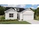Two-story home with white siding, black roof, and a two-car garage.Landscaped yard with shrubs at 124 Little Creek Dr, Lillington, NC 27546