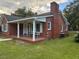 Side view of brick house, showcasing the covered porch and landscaping at 209 N Watauga Ave, Dunn, NC 28334