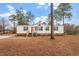 Newly remodeled single wide mobile home with red front door and pine trees at 97 Brent Wood Ct, Sanford, NC 27332