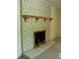 White brick fireplace with a wooden mantel and brass andirons at 1133 Evans Rd, Cary, NC 27513