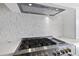 Stainless steel gas cooktop with modern range hood and backsplash at 8917 Grand Highland Way, Wake Forest, NC 27587