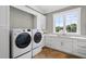 Bright laundry room, featuring white cabinets, hardwood floors and a large window at 8917 Grand Highland Way, Wake Forest, NC 27587