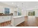 Open concept kitchen with island, white cabinets, and hardwood floors at 2269 Abbeyhill Dr # 133, Raleigh, NC 27610