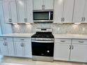 Modern kitchen featuring white cabinets, stainless steel appliances, and marble countertops at 112 Swain St, Clayton, NC 27527