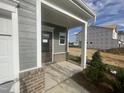 Front porch with gray siding, brick base, and double columns at 116 Commons Cir # 229, Clayton, NC 27520