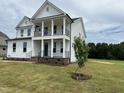 Two-story white house with a front porch and balcony, nestled in a green lawn at 123 Sage Ln # 010, Four Oaks, NC 27524