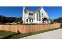 Modern farmhouse-style home with a wooden fence and lush green lawn at 3401 Makers Cir, Raleigh, NC 27612