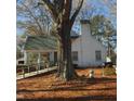 White home nestled among trees, featuring a sunroom and wooden ramp at 1852 Nc 62 Hwy N, Burlington, NC 27217