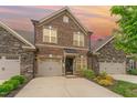 Attractive brick townhome exterior at sunset, featuring a two-car garage at 1121 Talisker Way, Burlington, NC 27215