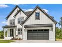 Two-story farmhouse with white siding, dark gray accents, and a three-car garage at 85 Harvest View Way, Franklinton, NC 27525