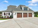 Three-car garage with light brown doors and landscaping at 8916 Grand Highland Way, Wake Forest, NC 27587