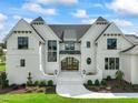 Front view of a white brick house with double doors and landscaping at 8916 Grand Highland Way, Wake Forest, NC 27587