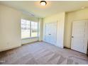 Spacious bedroom with large window, carpet, and double door closet at 117 Ausban Rdg Ln # 034, Four Oaks, NC 27524