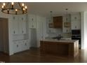 Spacious kitchen with island, white cabinets, and hardwood floors at 120 Summerlin Dr, Archer Lodge, NC 27527