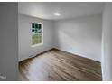 Simple bedroom with light walls, wood-look floors, and a large window at 825 Chalmers St, Durham, NC 27707