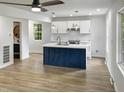Modern kitchen with white cabinets, a blue island, and new appliances at 825 Chalmers St, Durham, NC 27707