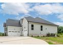 Side view of a house with a three-car garage and a paved driveway at 242 Lakestone Estates, Pittsboro, NC 27312