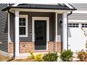 Front door entrance with gray siding and brick accents at 81 Hank Way, Angier, NC 27501