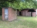 Brick outbuilding and red barn with wooden fence at 3124 Raleigh Rd, Henderson, NC 27537
