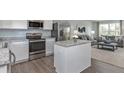 Open kitchen with island, stainless steel appliances, and hardwood floors at 4511 Black Drum Dr, Raleigh, NC 27616