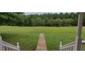 Landscaped backyard with a stone pathway leading to a lush green field at 1525 Marshburn Rd, Wendell, NC 27591