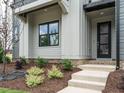 Inviting front entrance with gray siding, brick steps, and black front door at 1140 Cottonsprings Dr, Wendell, NC 27591