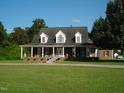 Brick ranch house with dormer windows, front porch, and a long driveway at 334 Ira B Tart Rd, Dunn, NC 28334