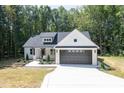 White farmhouse exterior with black garage door and landscaping at 114 Shaman Dr, Louisburg, NC 27549