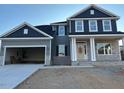 Two-story home with gray and blue siding, stone accents, and a three-car garage at 84 Rosslyn Way # 92, Garner, NC 27529