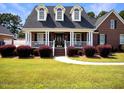 Brick home with a front porch, landscaping, and a three-car garage at 107 Knottingham Ct, Dunn, NC 28334