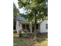 A white, ranch-style house with a covered porch and mature trees in the front yard at 4285 Belltown Rd, Oxford, NC 27565