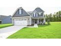 Two-story home with gray siding, stone accents, and a white two-car garage at 236 Abingdon Farms Dr, Selma, NC 27576