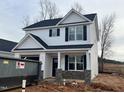 Two-story Craftsman style home with white siding, gray stone accents, and a black roof at 35 S Mistflower St, Clayton, NC 27520