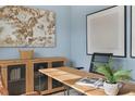 Home office with light blue walls, wooden desk, and large artwork at 6421 Alfalfa Ln, Wake Forest, NC 27587